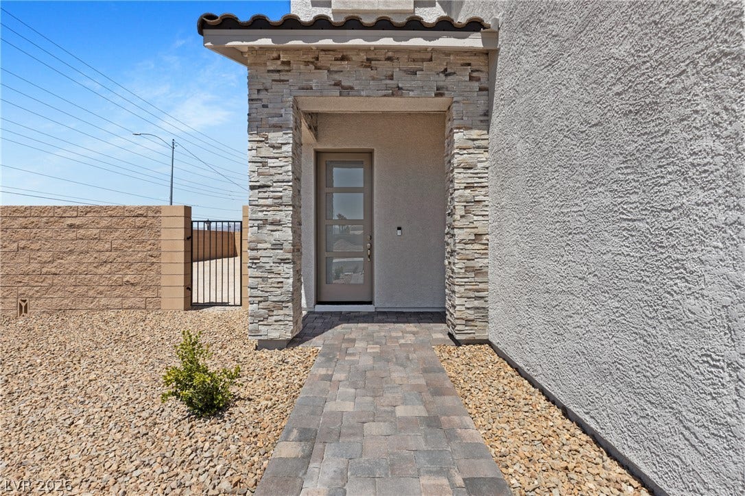 2405 Copperbelt Street, Las Vegas, NV 89030 A welcoming entry features stacked stone accents and a paver pathway leading to the front door.