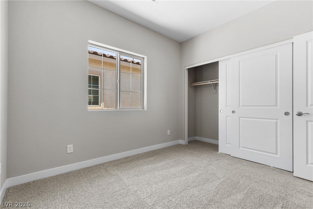 2405 Copperbelt Street, Las Vegas, NV 89030 A well-lit bedroom features plush carpeting and a spacious closet with bi-fold doors.