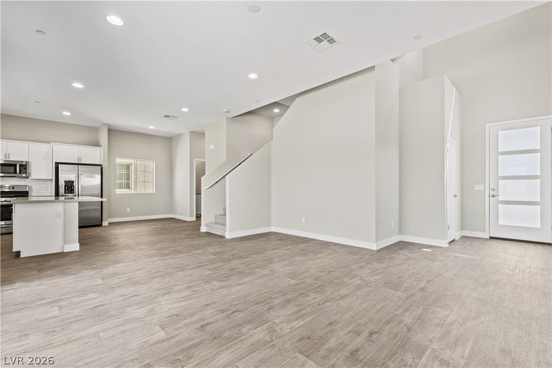 2405 Copperbelt Street, Las Vegas, NV 89030 A spacious, open-concept interior featuring light wood flooring and a modern kitchen with stainless steel appliances.