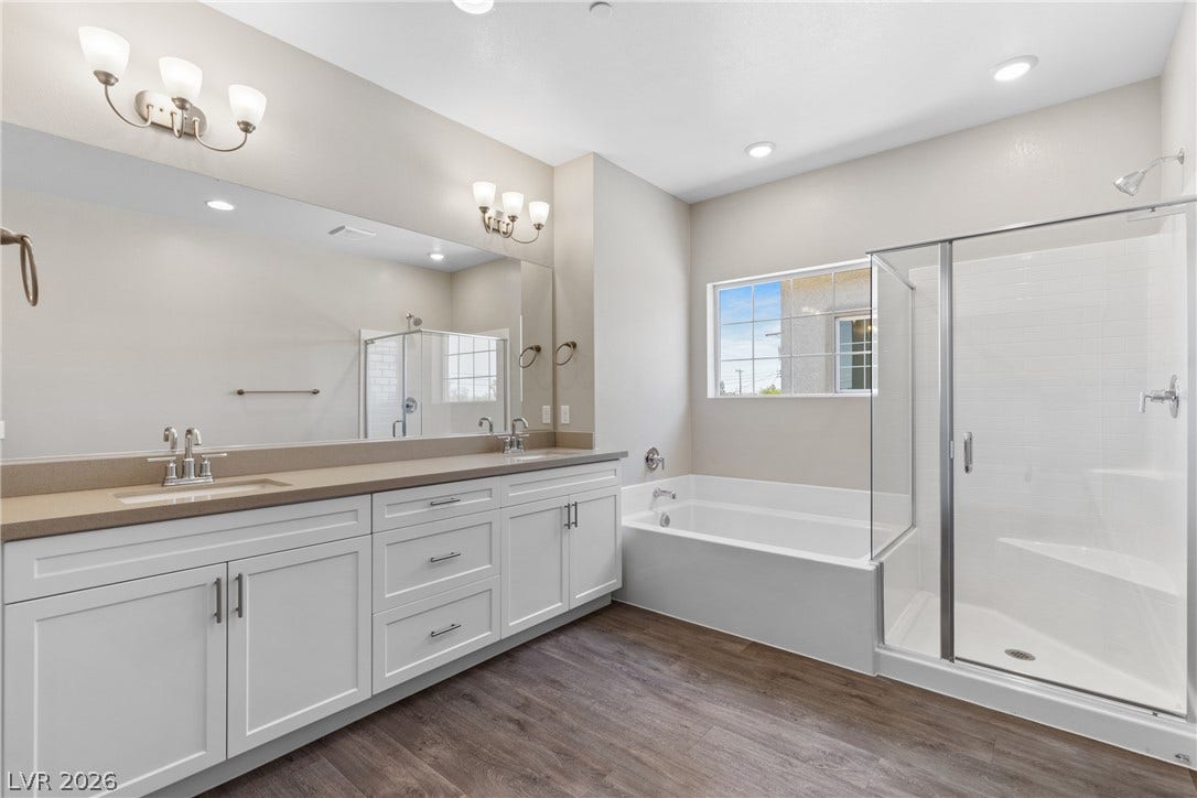 2405 Copperbelt Street, Las Vegas, NV 89030 A refined bathroom featuring a spacious dual vanity, a soaking tub, and a sleek walk-in shower.