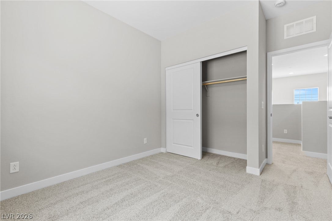 2405 Copperbelt Street, Las Vegas, NV 89030 Well-lit room with plush carpet, featuring an accessible closet with sliding doors, offering an inviting blank canvas.