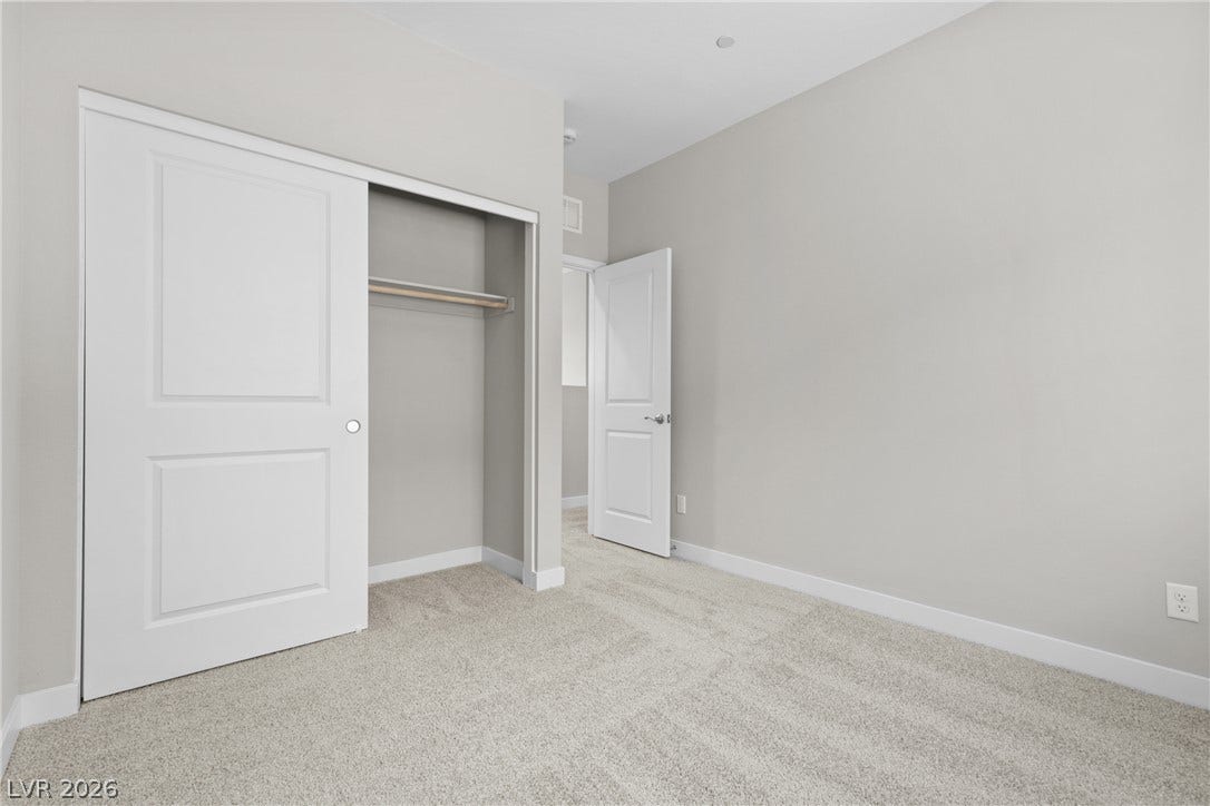 2405 Copperbelt Street, Las Vegas, NV 89030 A well-lit bedroom features plush carpeting and a spacious sliding door closet.