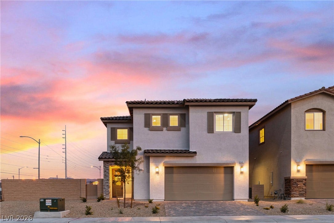2405 Copperbelt Street, Las Vegas, NV 89030 This modern home features a spacious attached garage, complemented by stone accents and warm exterior lighting.