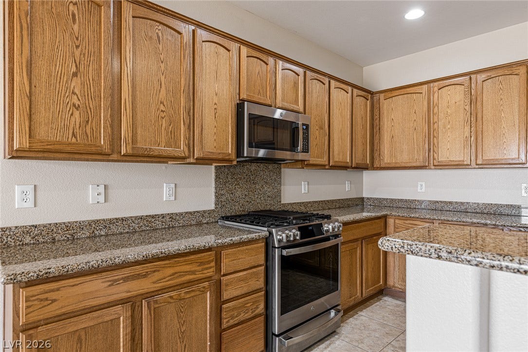2157 Sawtooth Mountain Drive, Henderson, NV 89044 A well-appointed kitchen features rich wooden cabinetry and polished granite countertops and backsplash.