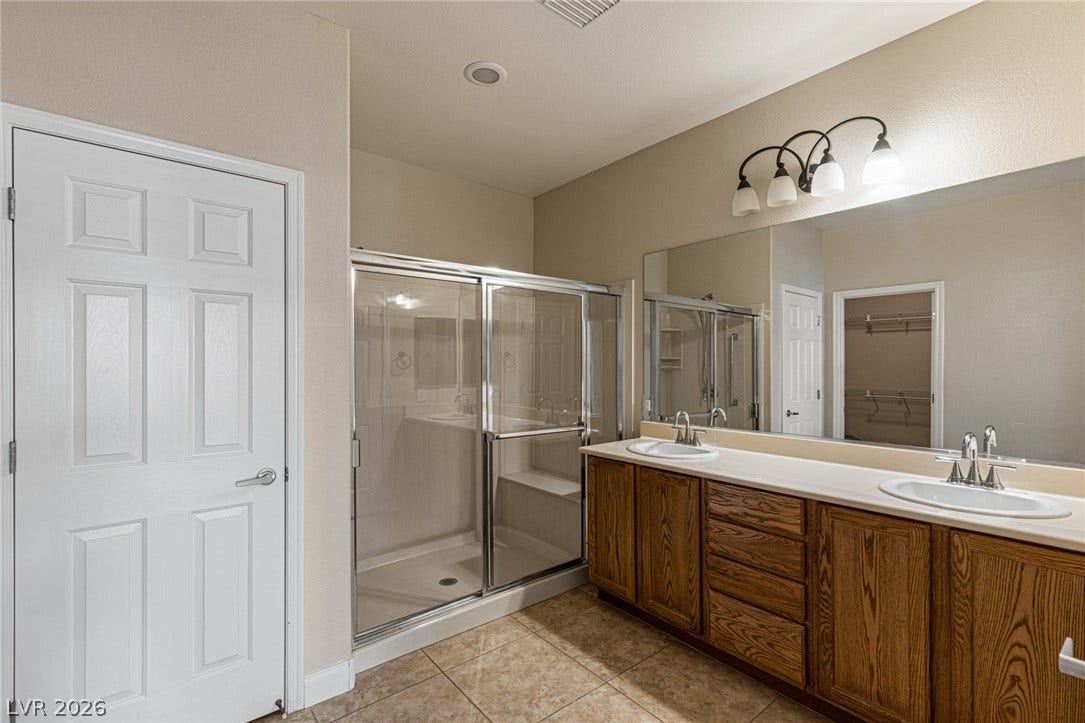 2157 Sawtooth Mountain Drive, Henderson, NV 89044 A well-appointed primary bathroom features a double vanity and a glass-enclosed shower with linen closet.