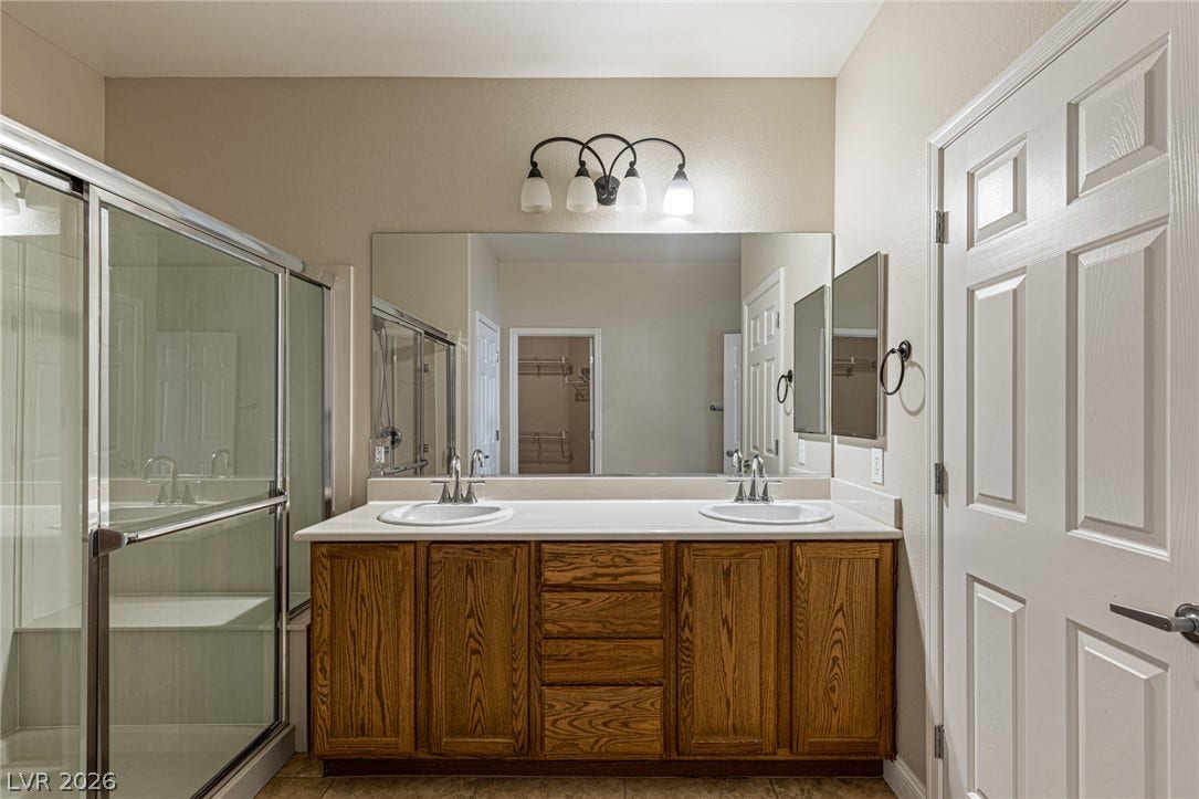 2157 Sawtooth Mountain Drive, Henderson, NV 89044 Double vanity and spacious glass-enclosed shower with bench, grab bar, and hand held shower.