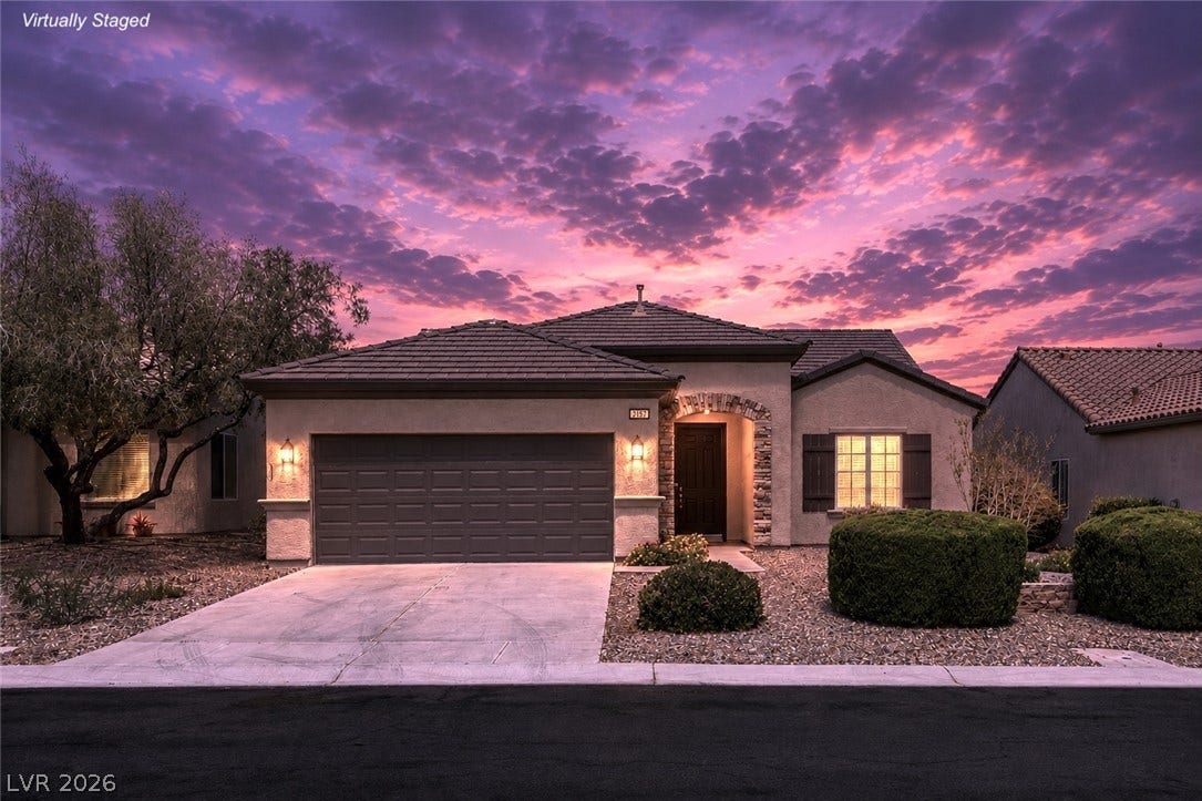 2157 Sawtooth Mountain Drive, Henderson, NV 89044 Dramatic sunset hues illuminate the exterior of this inviting home with charming stone accents.
