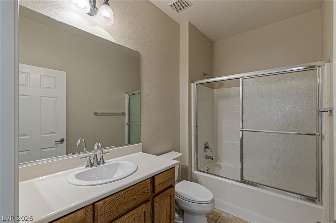 2157 Sawtooth Mountain Drive, Henderson, NV 89044 A well-appointed bathroom features a single vanity, ample mirror, and a convenient shower-over-tub setup.