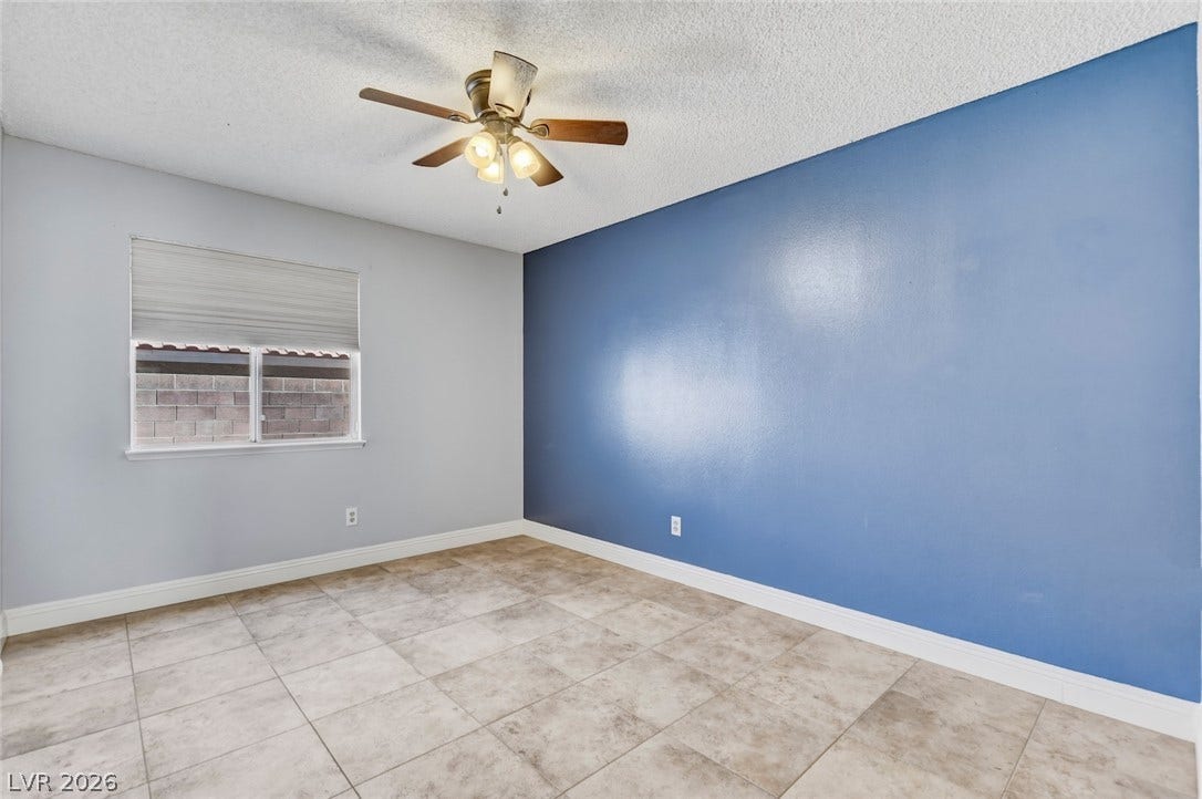 1827 Escondido Terrace, Henderson, NV 89074 A well-lit bedroom with tile flooring features a ceiling fan, perfect for year-round comfort.