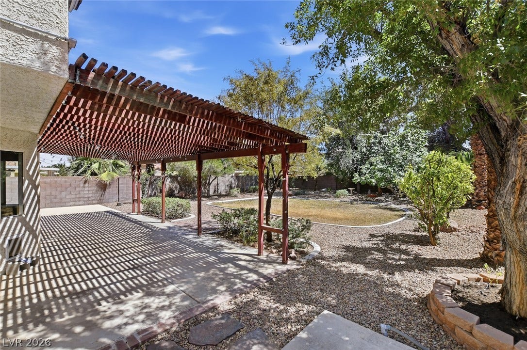 1827 Escondido Terrace, Henderson, NV 89074 A spacious backyard retreat features a wooden pergola offering dappled shade over the concrete patio.