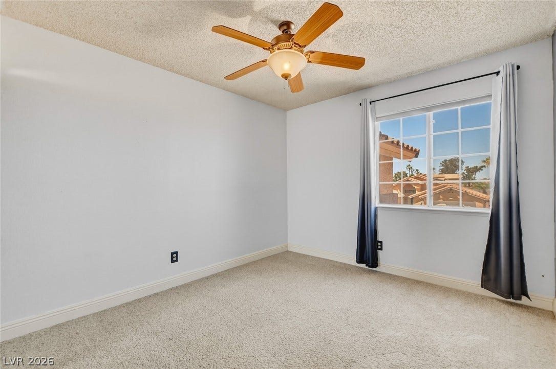 1827 Escondido Terrace, Henderson, NV 89074 A quiet bedroom offers comfort with soft carpeting and a ceiling fan, providing a peaceful retreat.