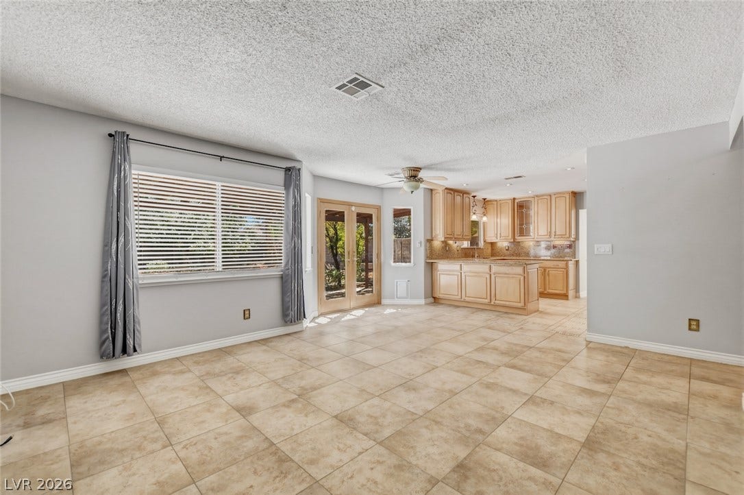 1827 Escondido Terrace, Henderson, NV 89074 A spacious living area with warm-toned tile flooring and natural light, flowing into a well-appointed kitchen.