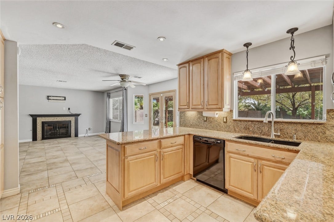 1827 Escondido Terrace, Henderson, NV 89074 A vibrant kitchen with granite counters opens to a welcoming living space featuring a cozy fireplace.