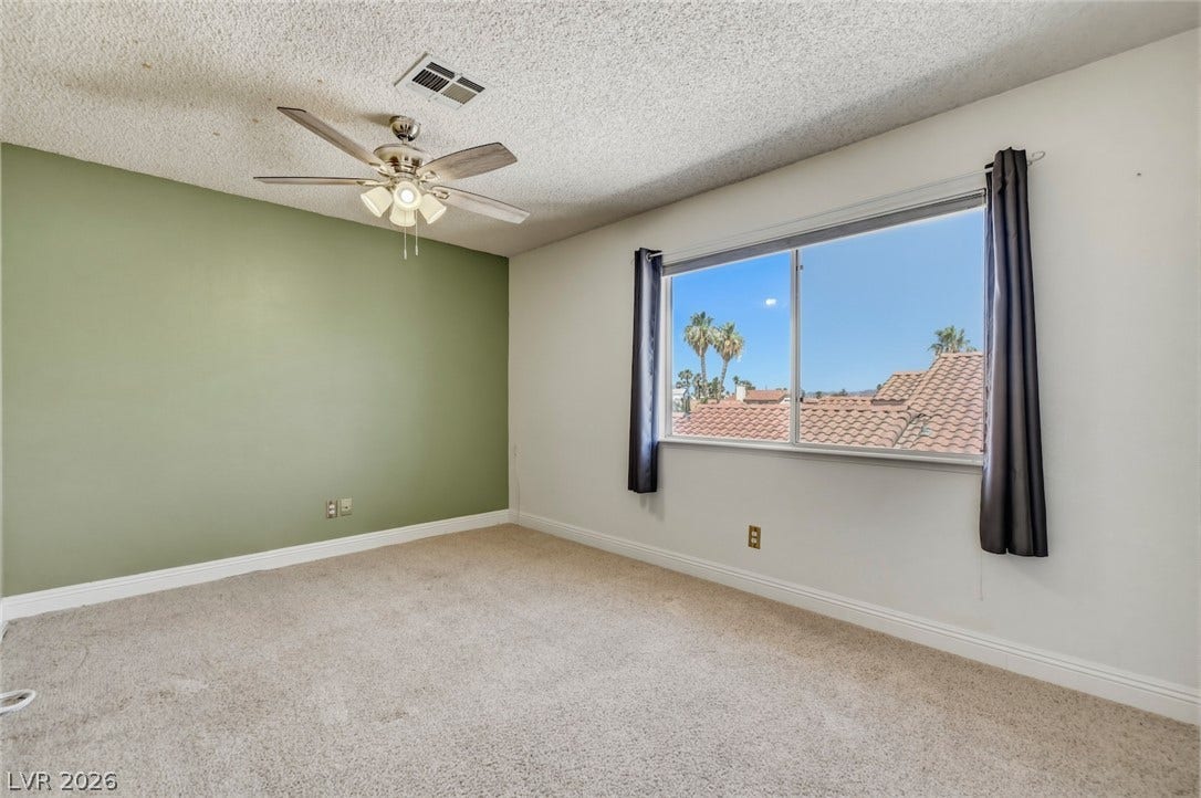 1827 Escondido Terrace, Henderson, NV 89074 A well-lit bedroom features plush carpeting and a convenient ceiling fan for optimal comfort.