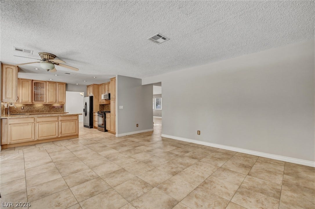 1827 Escondido Terrace, Henderson, NV 89074 A well-appointed kitchen features ample cabinetry and a practical breakfast bar flowing into an open-concept living space.