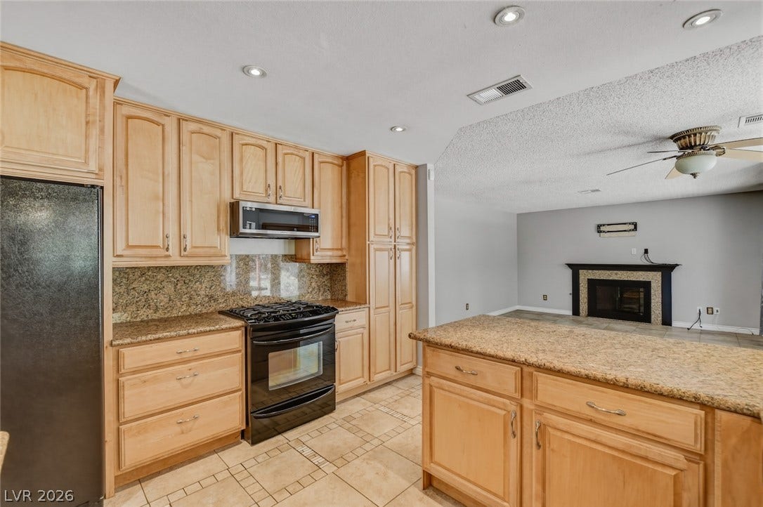 1827 Escondido Terrace, Henderson, NV 89074 A well-appointed kitchen flows seamlessly into the inviting living area with a fireplace, ideal for gatherings.