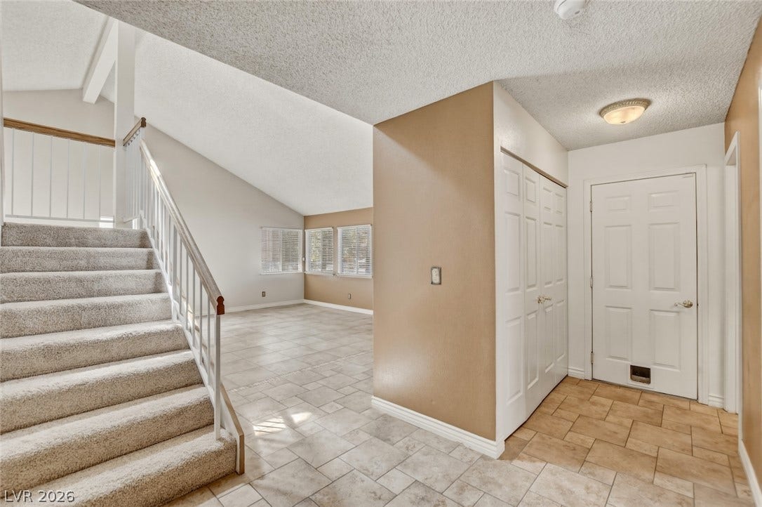 1827 Escondido Terrace, Henderson, NV 89074 A well-lit interior with vaulted ceilings, blending carpeted stairs with tiled living areas.
