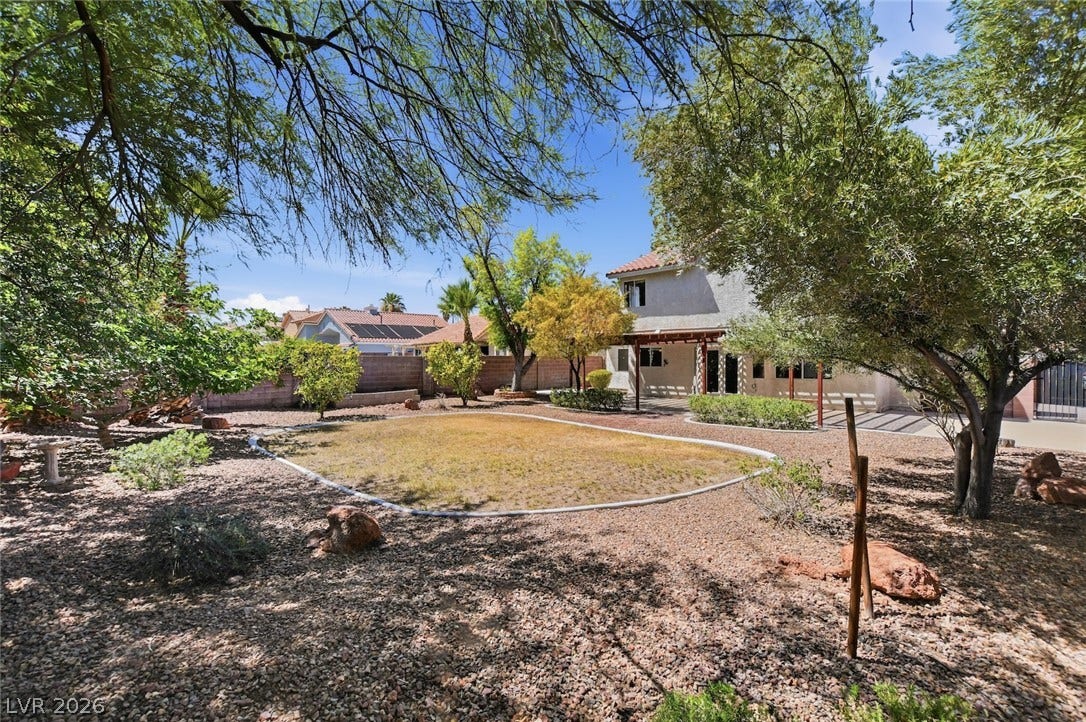 1827 Escondido Terrace, Henderson, NV 89074 A spacious backyard with mature trees and a desert-adapted landscape offers serene outdoor living.