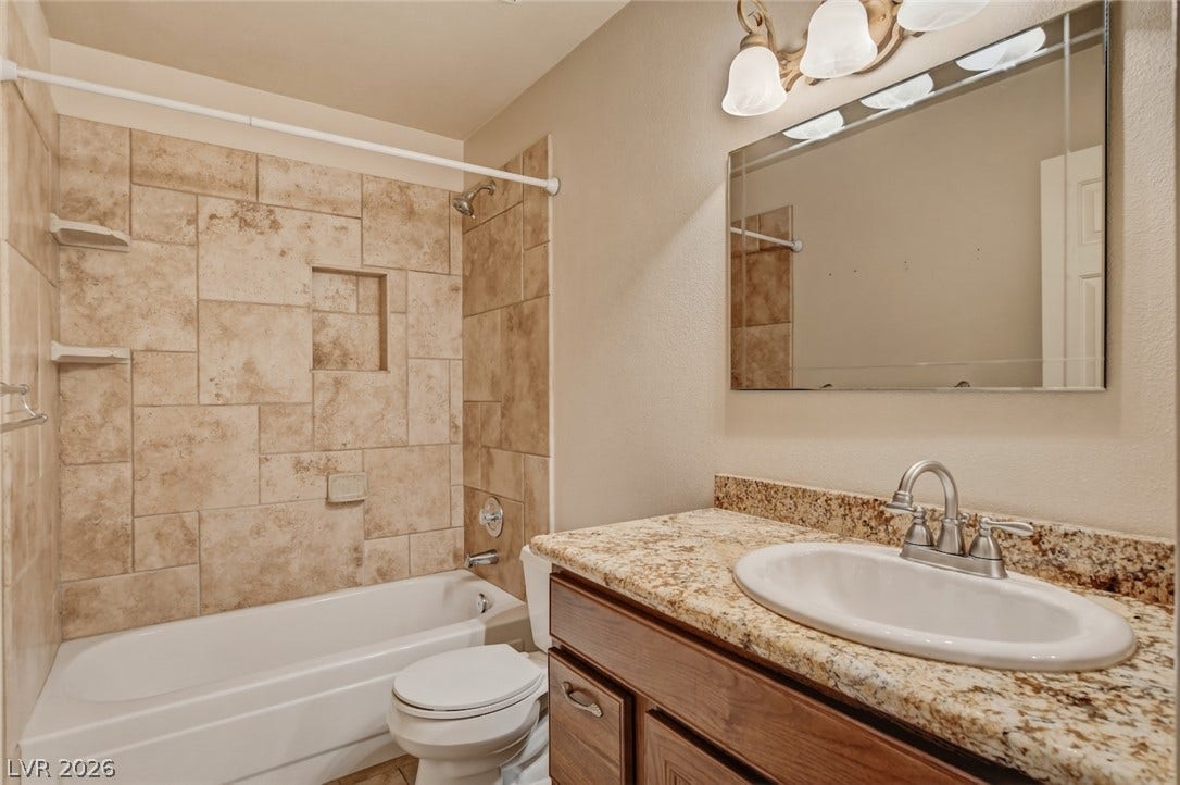 1827 Escondido Terrace, Henderson, NV 89074 Tiled bath and shower with recessed shelving, complemented by a stone-topped vanity.