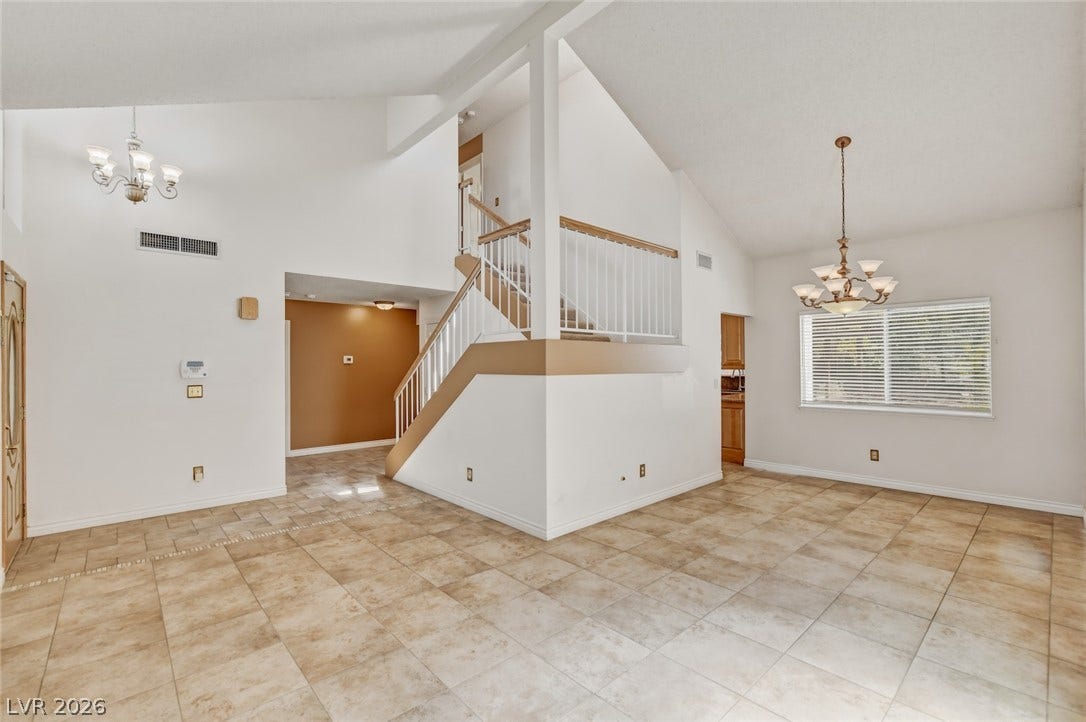 1827 Escondido Terrace, Henderson, NV 89074 Vast tile flooring ushers guests into this versatile living space, featuring high vaulted ceilings and a grand staircase.