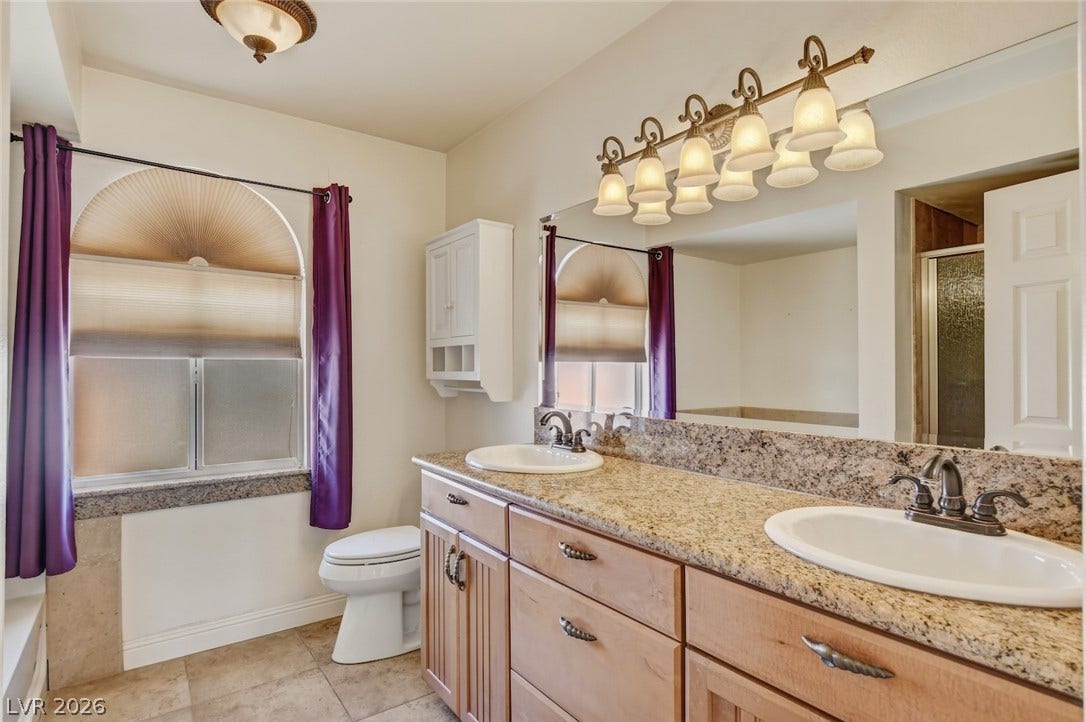 1827 Escondido Terrace, Henderson, NV 89074 Double vanity with granite counters and rich cabinetry defines this ample bathroom space.