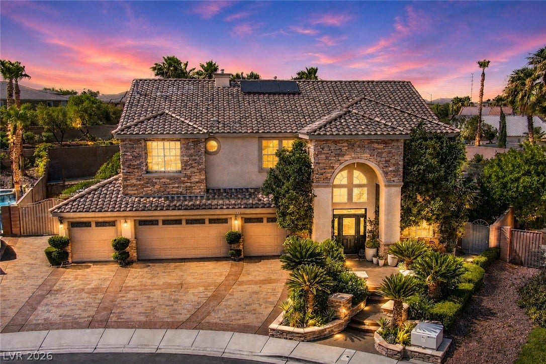 699 Brandy Hill Place, Henderson, NV 89052 Mediterranean-inspired architecture with warm outdoor lighting offers inviting curb appeal.