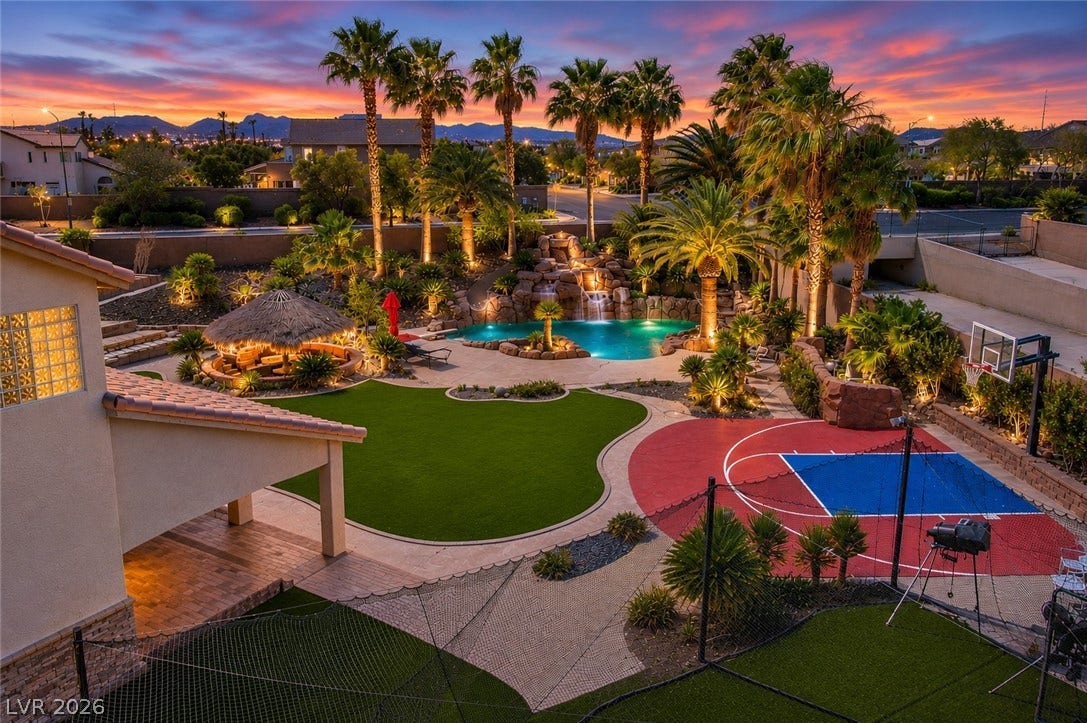 699 Brandy Hill Place, Henderson, NV 89052 An oasis of fun under a vibrant sky, featuring a custom pool with waterfall, sports court, and lush landscaping.