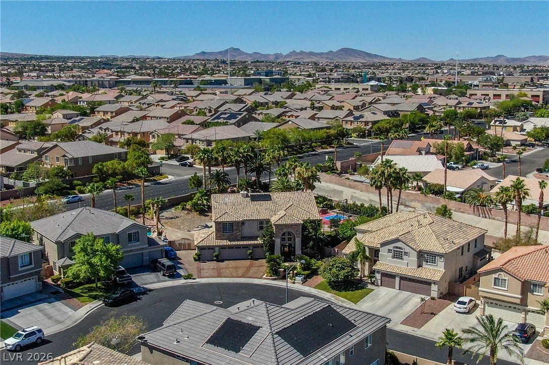 699 Brandy Hill Place, Henderson, NV 89052 An aerial perspective reveals a vibrant neighborhood with diverse architectural styles, nestled against a backdrop of distant mountains.