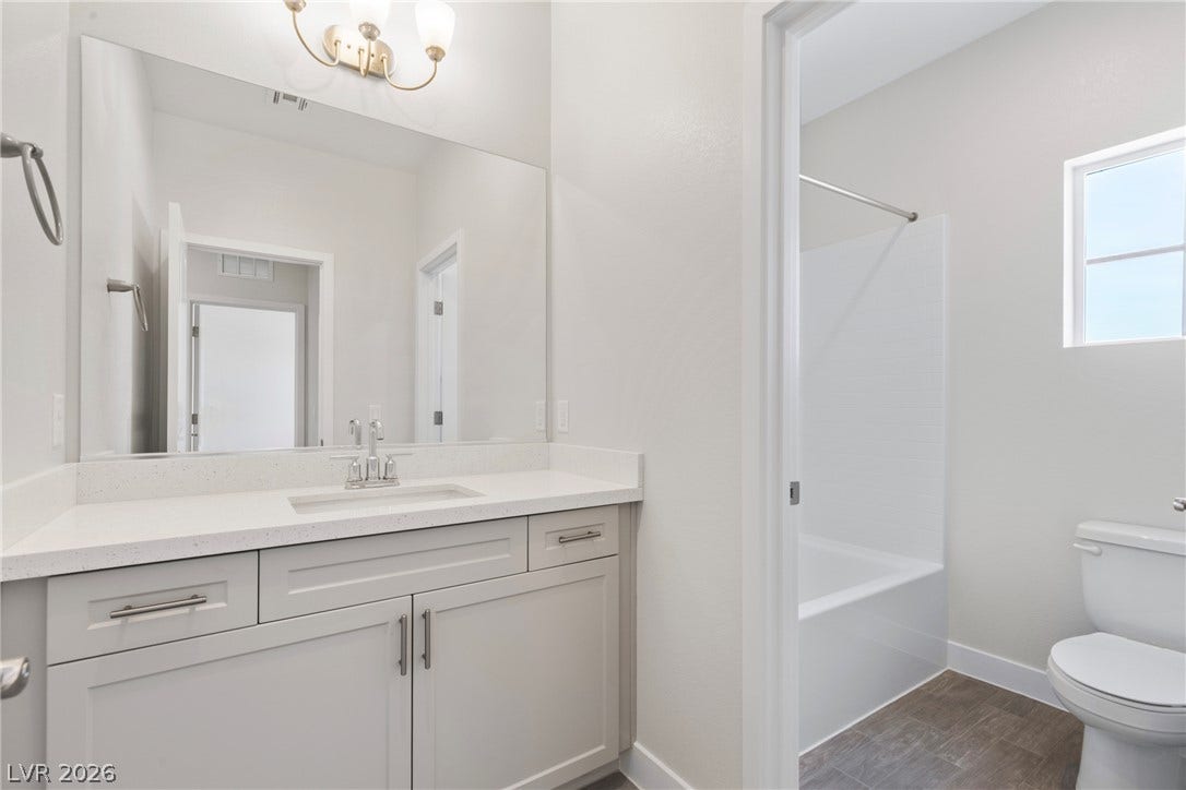 A modern bathroom features a clean white vanity and a built-in tub shower combination.