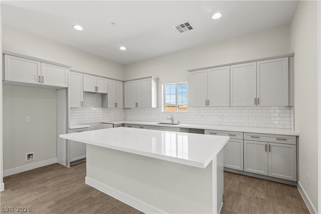 Clean lines and stone countertops define this spacious, modern cooking area.
