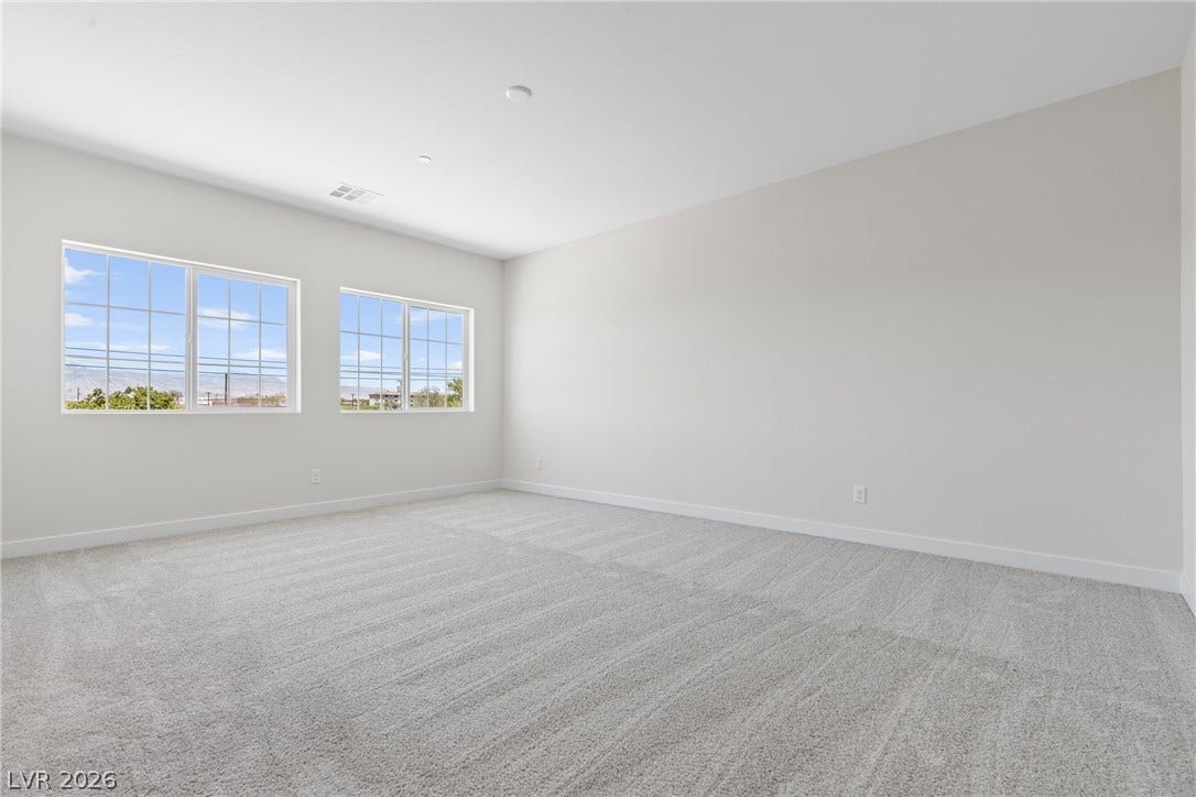 Plush carpeting and dual windows define this serene, minimalist bedroom space.