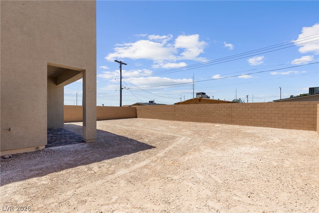 An enclosed block wall surrounds a generous, unpaved outdoor area with infinite potential.