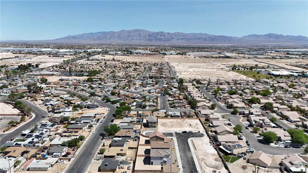 An expansive neighborhood panorama captures the vast desert valley stretching toward majestic distant mountains.