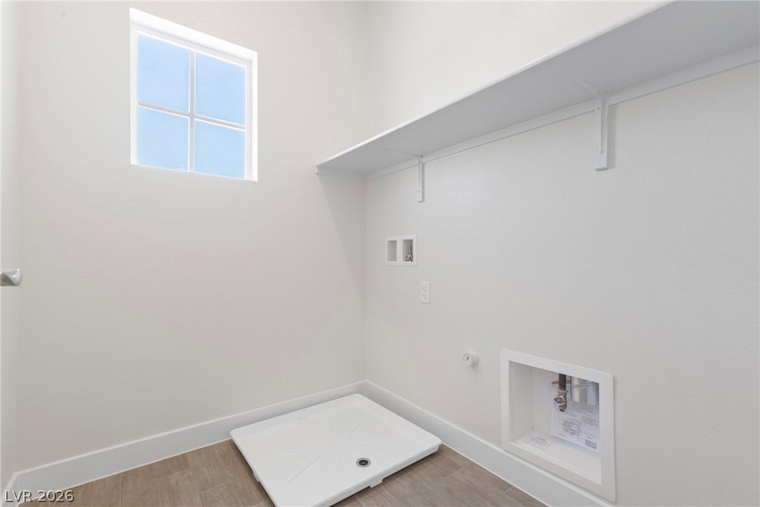 A dedicated utility space features high ceilings, built-in shelving, and a natural light source.