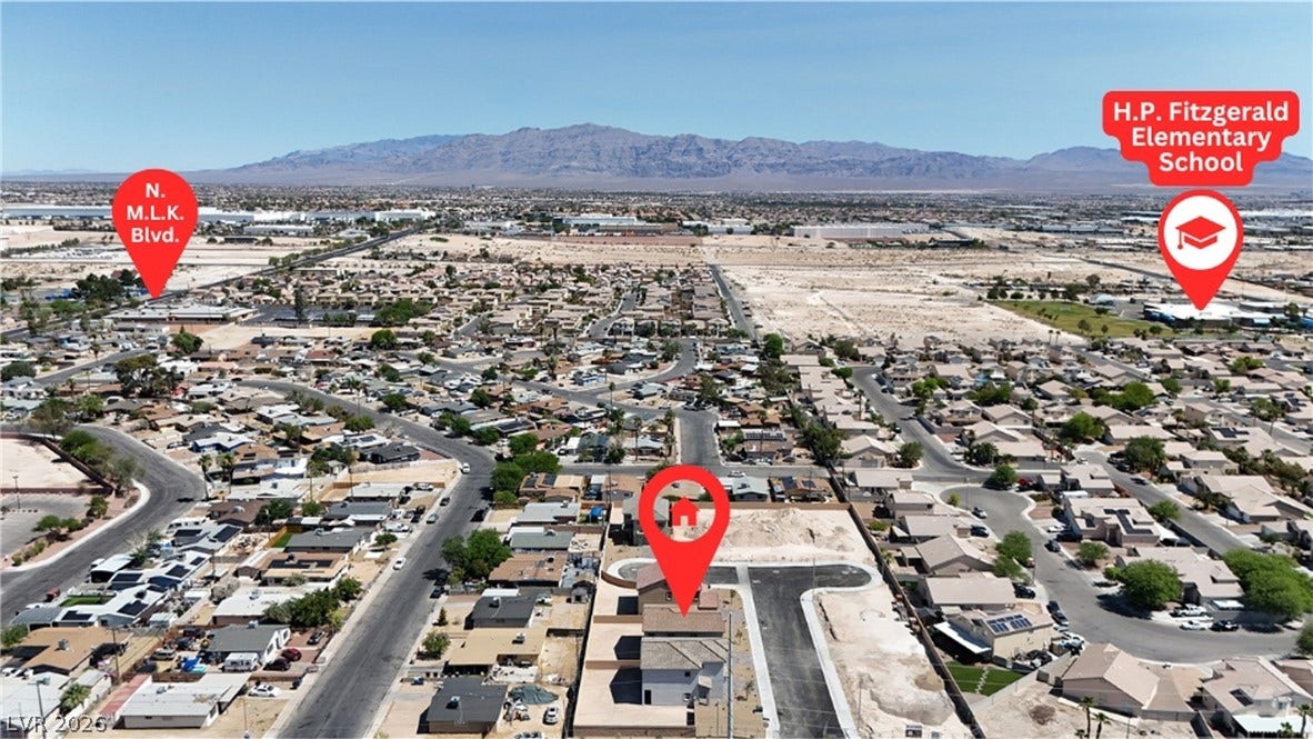 An aerial perspective showcases the surrounding neighborhood and distant mountain range.