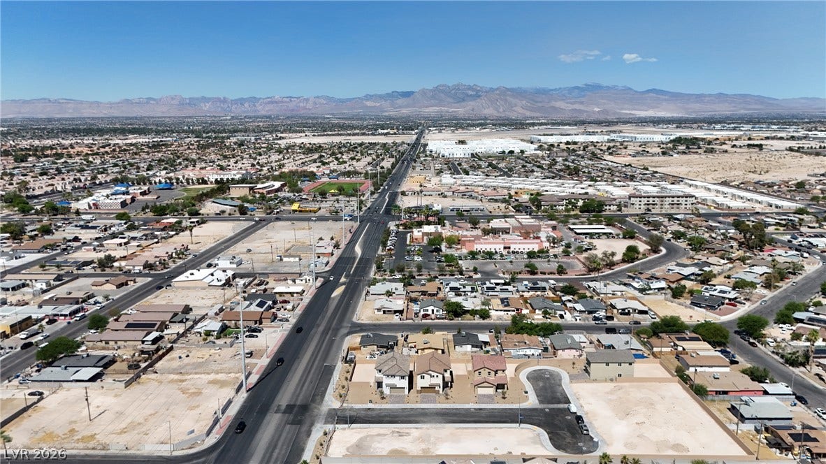 An aerial perspective showcases a developing suburban neighborhood backdropped by majestic mountain ranges.