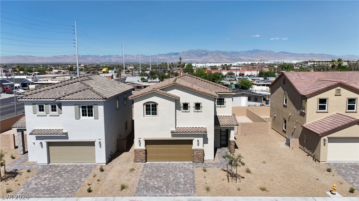 Distant mountain ranges frame a modern neighborhood lined with tiled roofs and paved driveways.