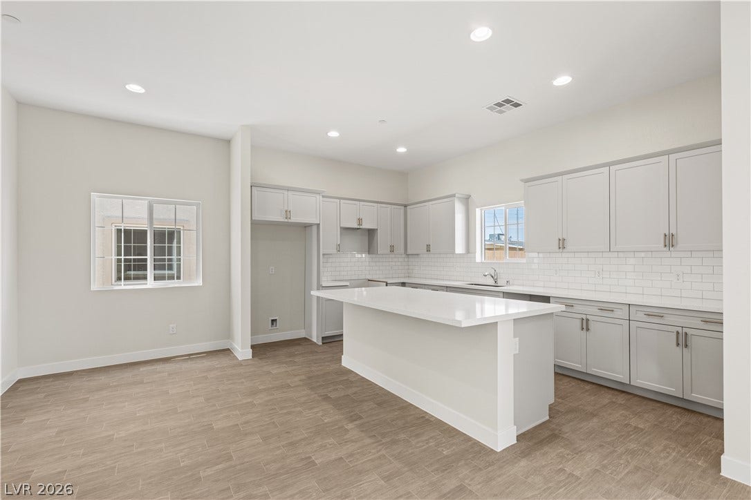 Gleaming stone countertops and recessed lighting elevate this modern kitchen featuring a central island.