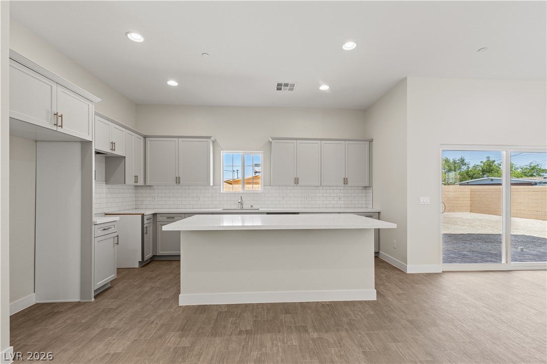 Gleaming stone countertops and recessed lighting anchor this open modern kitchen space.