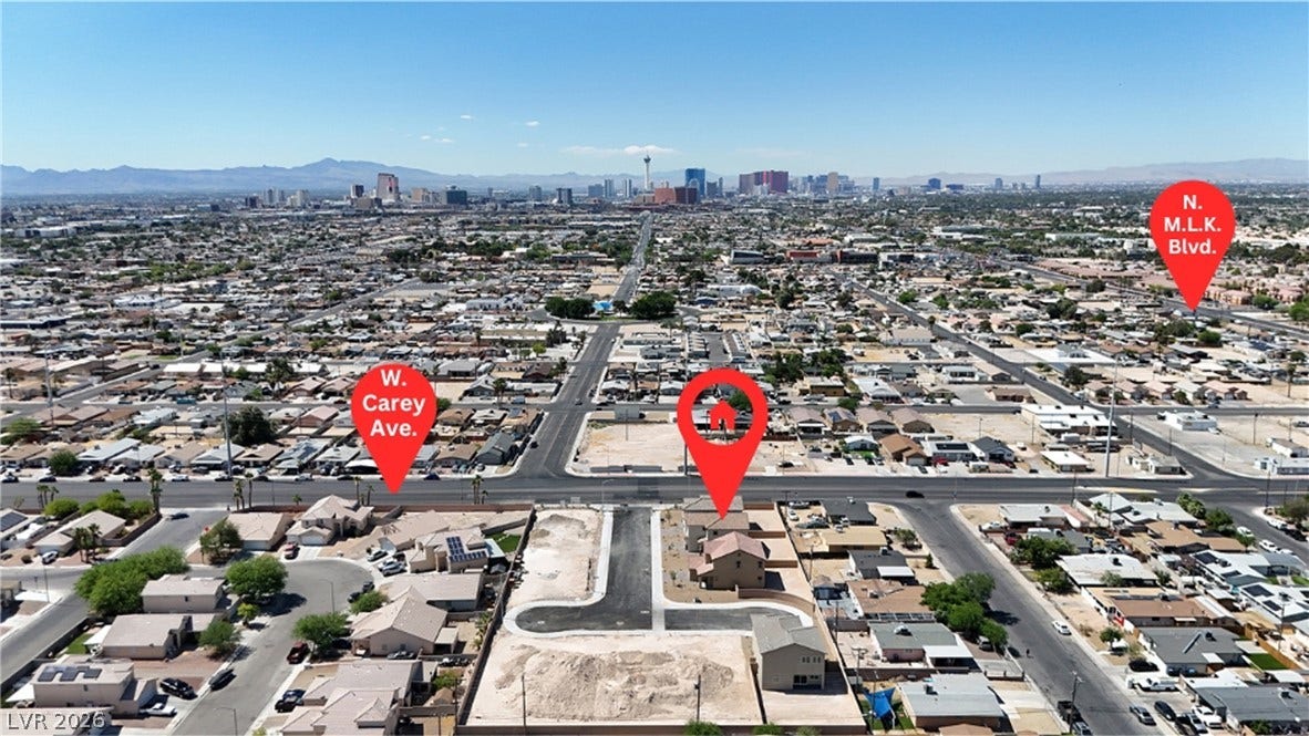A high-altitude aerial view reveals the surrounding suburban neighborhood and distant city skyline.
