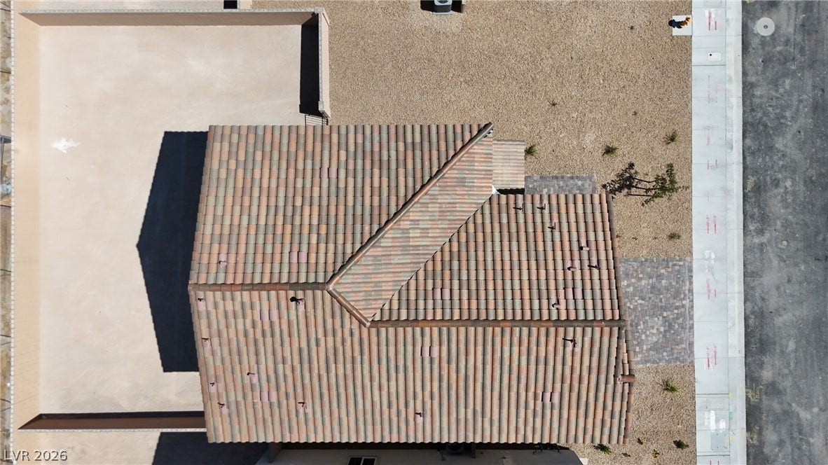 A top-down aerial view highlights the tile roof and surrounding desert landscaping.