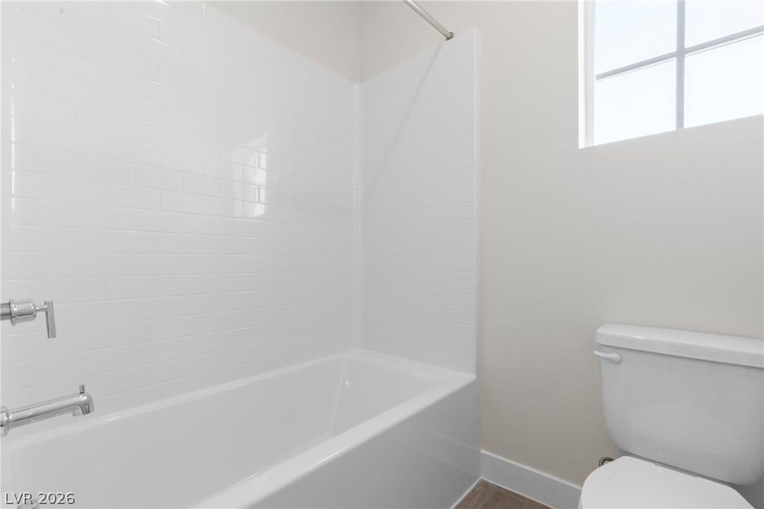 Crisp subway tile surrounds the built-in bathtub next to a classic multi-lite window.