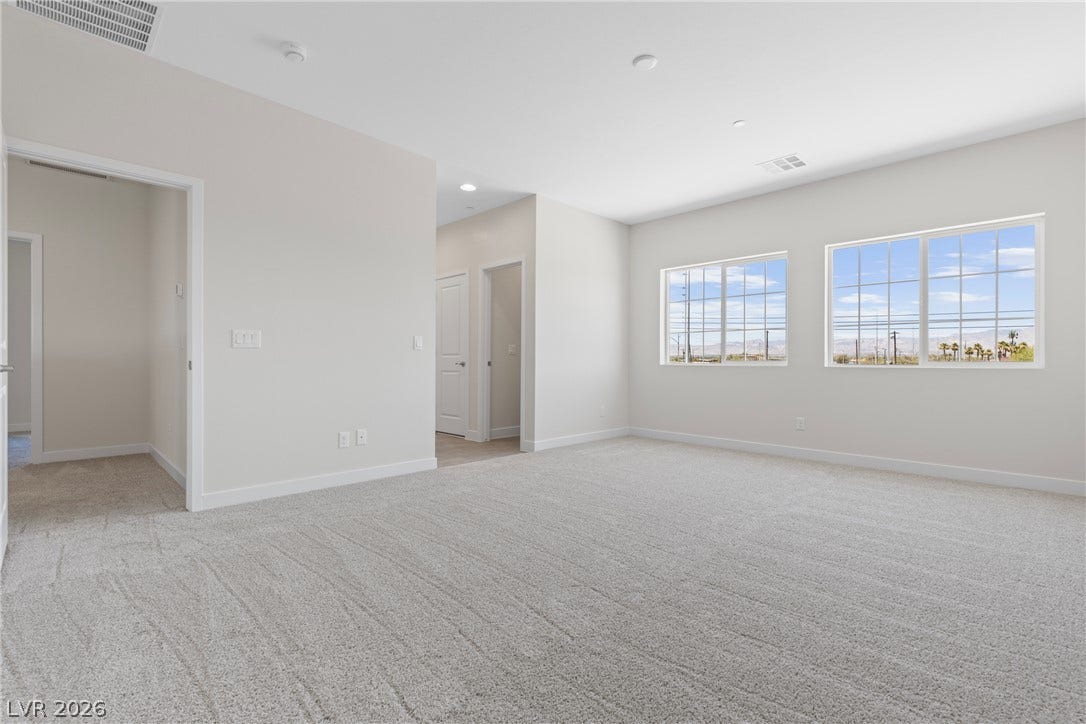 A spacious secondary living area features soft carpeting, recessed lighting, and multi-pane windows.