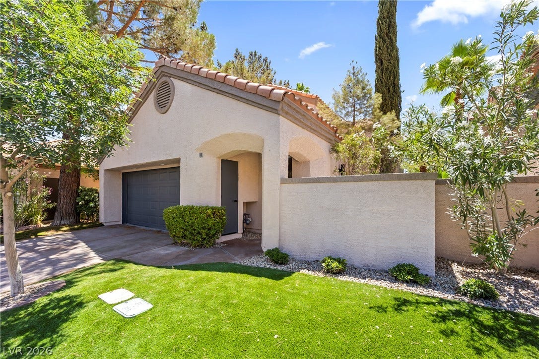 8921 Diamond Falls Drive, Las Vegas, NV 89117 A charming stucco home with a terracotta roof, surrounded by vibrant landscaping and a manicured lawn.