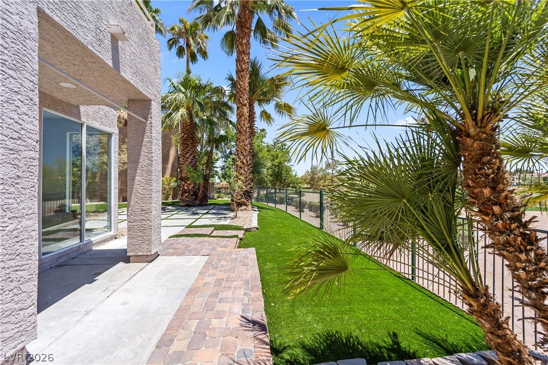 8921 Diamond Falls Drive, Las Vegas, NV 89117 A well-maintained side yard features lush artificial turf and mature palm trees along a secure fence.