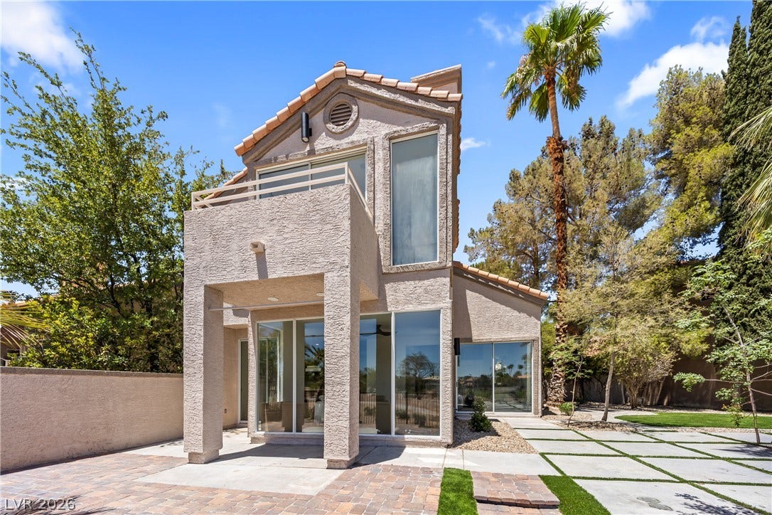 8921 Diamond Falls Drive, Las Vegas, NV 89117 A modern facade with a private balcony overlooks a patterned concrete and grass driveway.