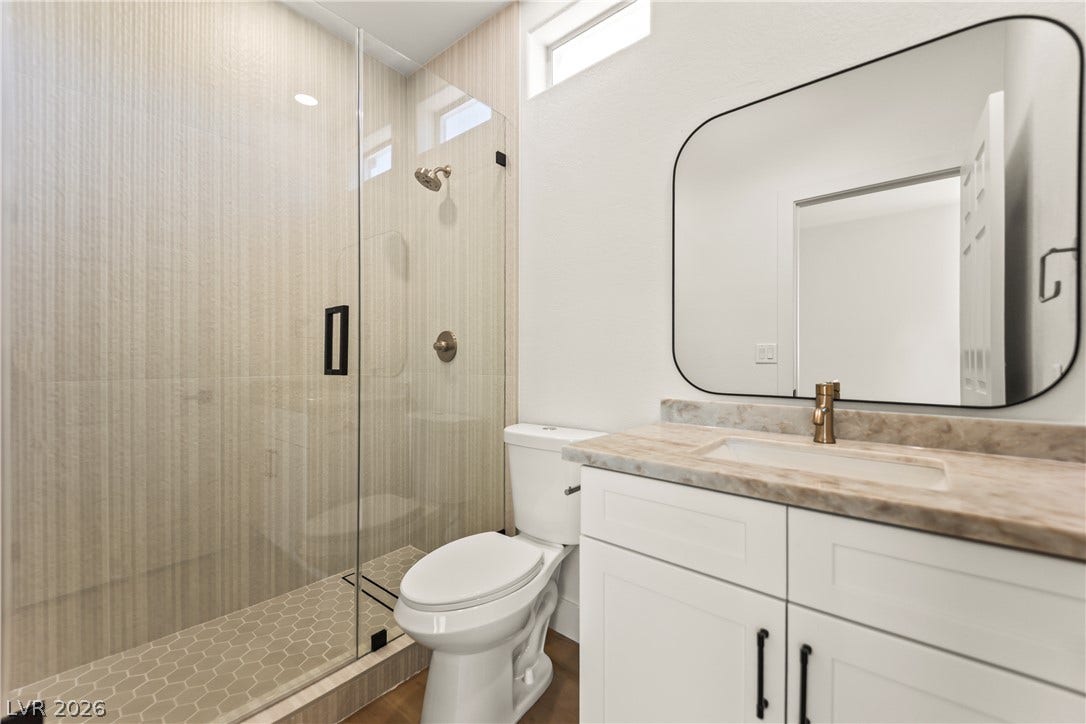 8921 Diamond Falls Drive, Las Vegas, NV 89117 A well-appointed bathroom features a spacious glass-enclosed shower and contemporary vanity.