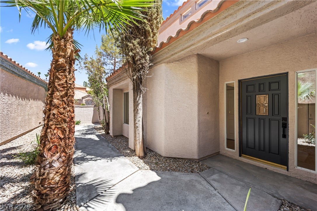8921 Diamond Falls Drive, Las Vegas, NV 89117 A welcoming entry path leads to a solid front door, flanked by narrow windows and desert landscaping.