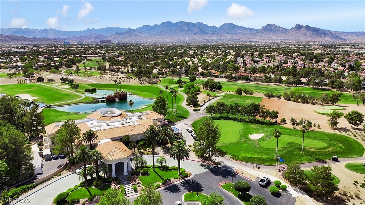 8921 Diamond Falls Drive, Las Vegas, NV 89117 An aerial panorama reveals a golf course, clubhouse, and lush surroundings against a mountain backdrop.