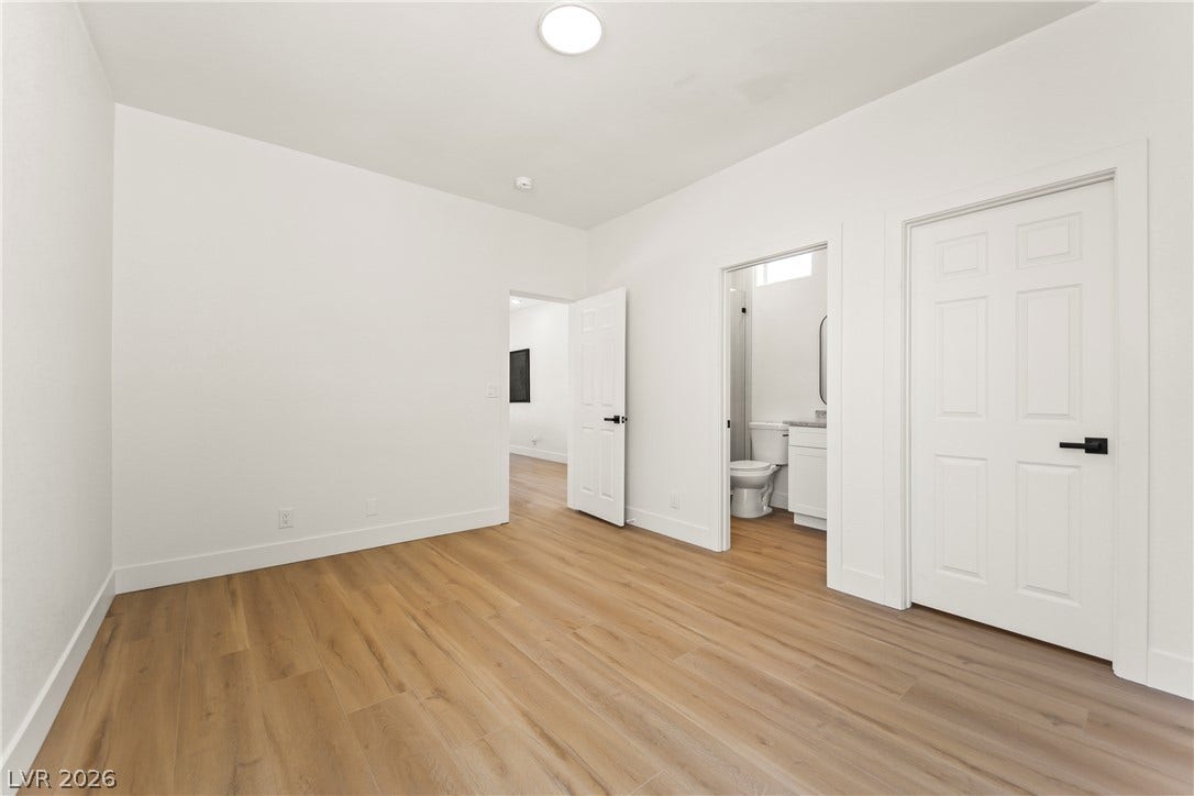 8921 Diamond Falls Drive, Las Vegas, NV 89117 A well-lit bedroom features durable hardwood flooring and convenient access to a modern bathroom.